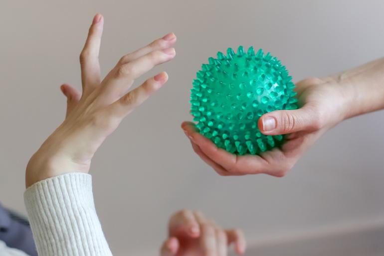 Photo of a person's hand holding a textured ball and handing it to another person's hands