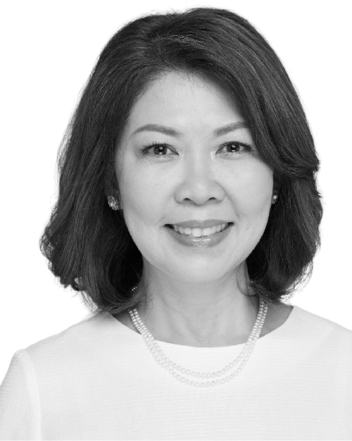 Black and white photo of Peggy Sarah Yee, she is smiling, has shoulder length hair and is wearing a white top